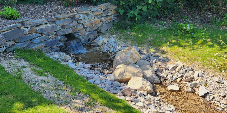 Small pebble lined creek setting and grassy banks with a waterwise fitted water flow system