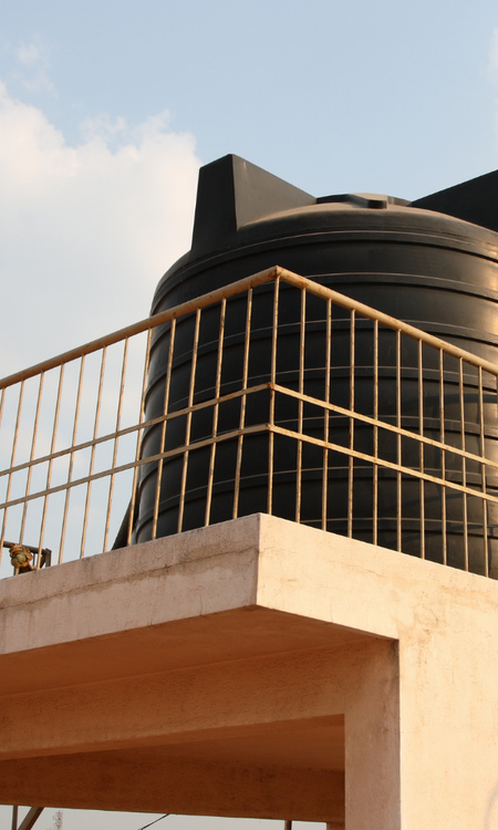 Potable water tank on an elevated concrete platform in a sunny outdoor setting.