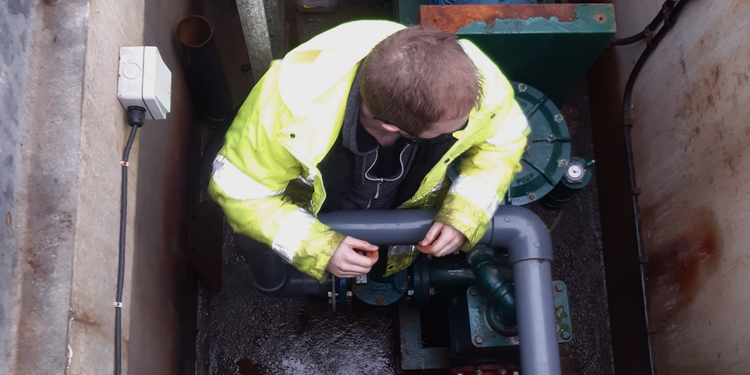 One of our waterwise team members on site in an underground setting. Inspecting a water flow system with a hi-vis jacket.